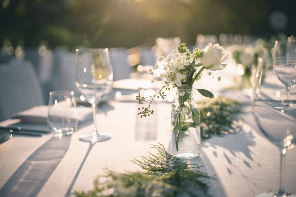 Beautiful outdoor table setting with white flowers for a dinner, wedding reception or other festive event.